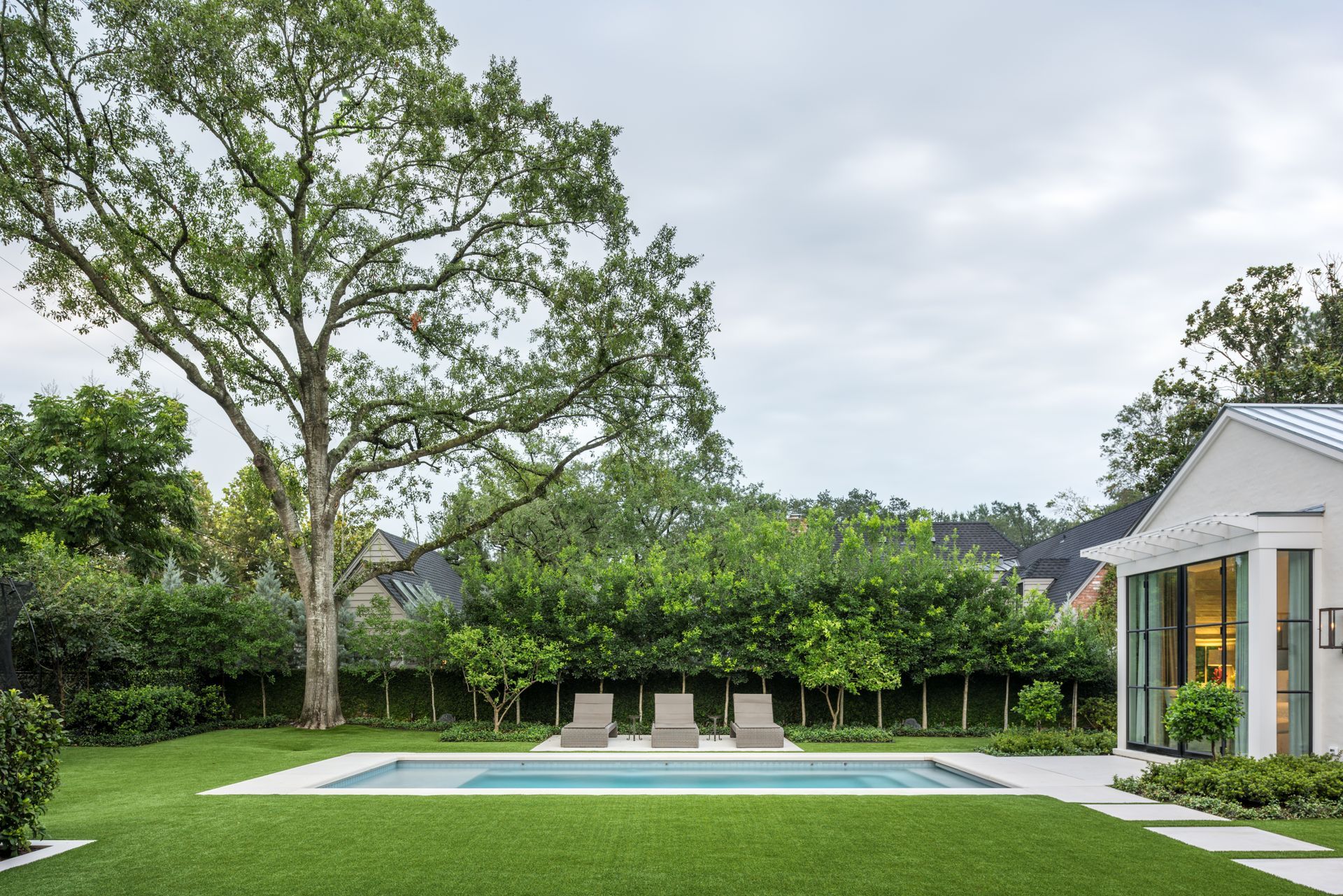 there is a large swimming pool in the backyard of a house .