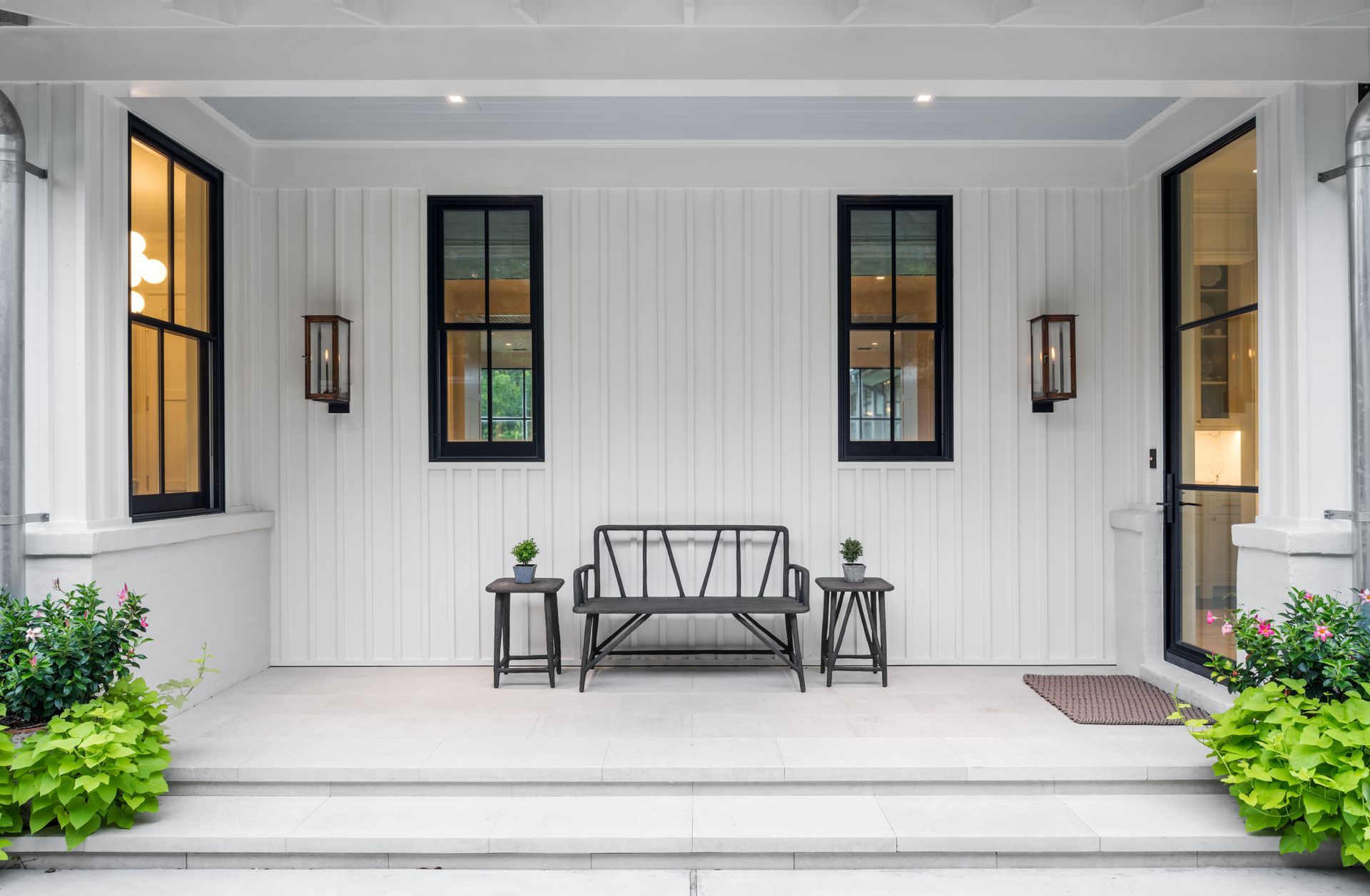 a white house with black windows and a bench on the porch .
