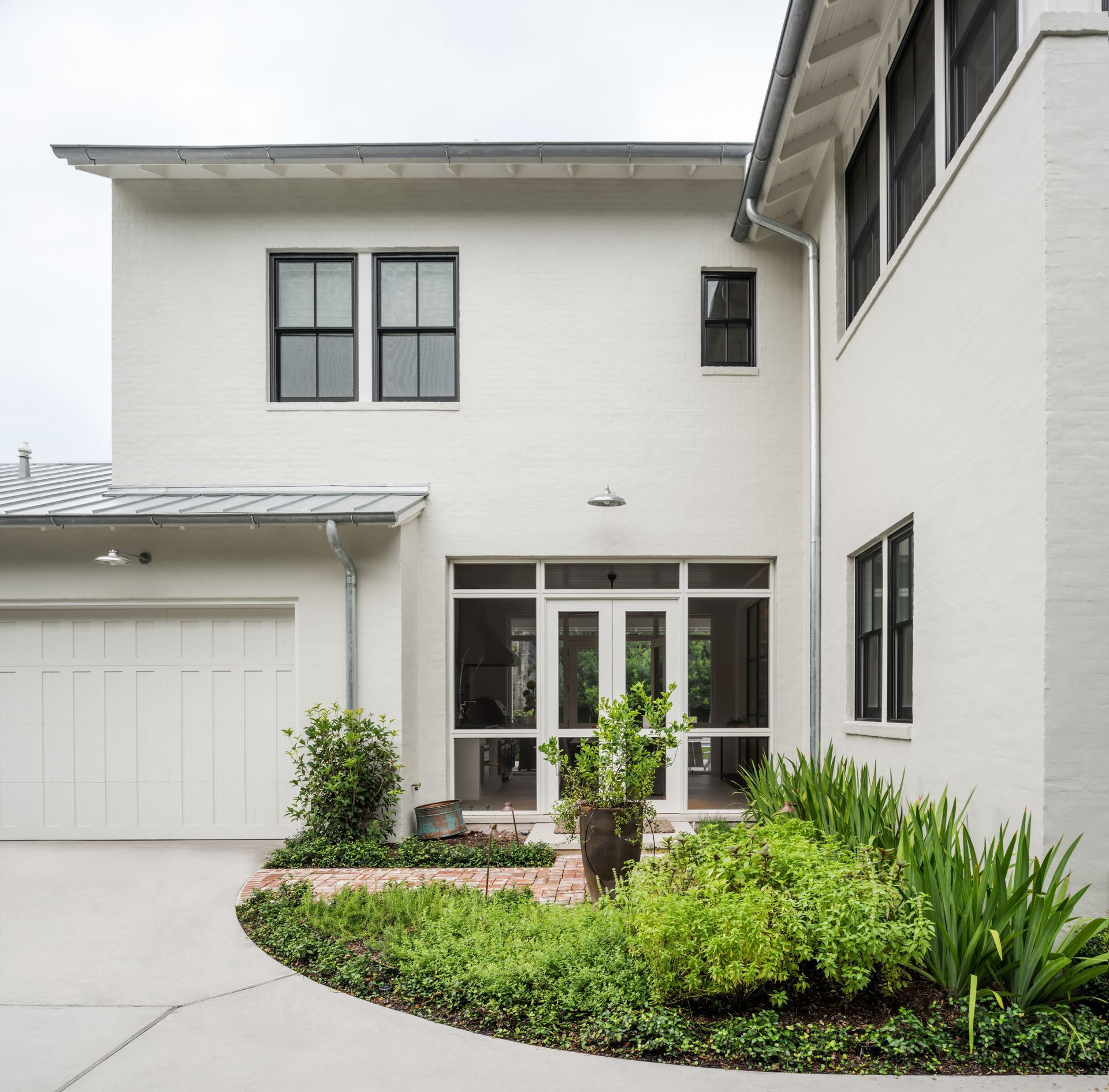 a white house with a garage and a garden in front of it