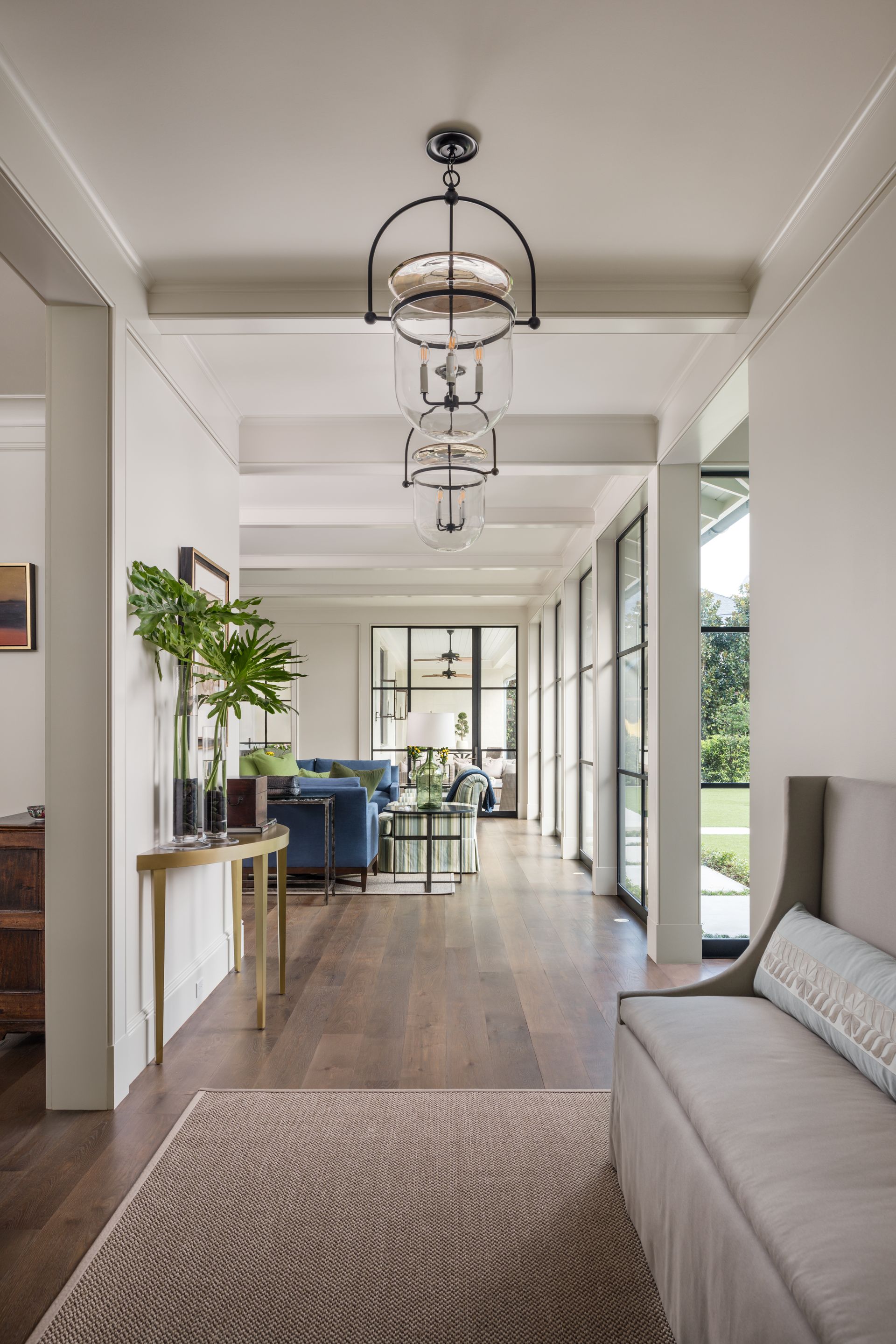 a long hallway leading to a living room with a couch and a rug .