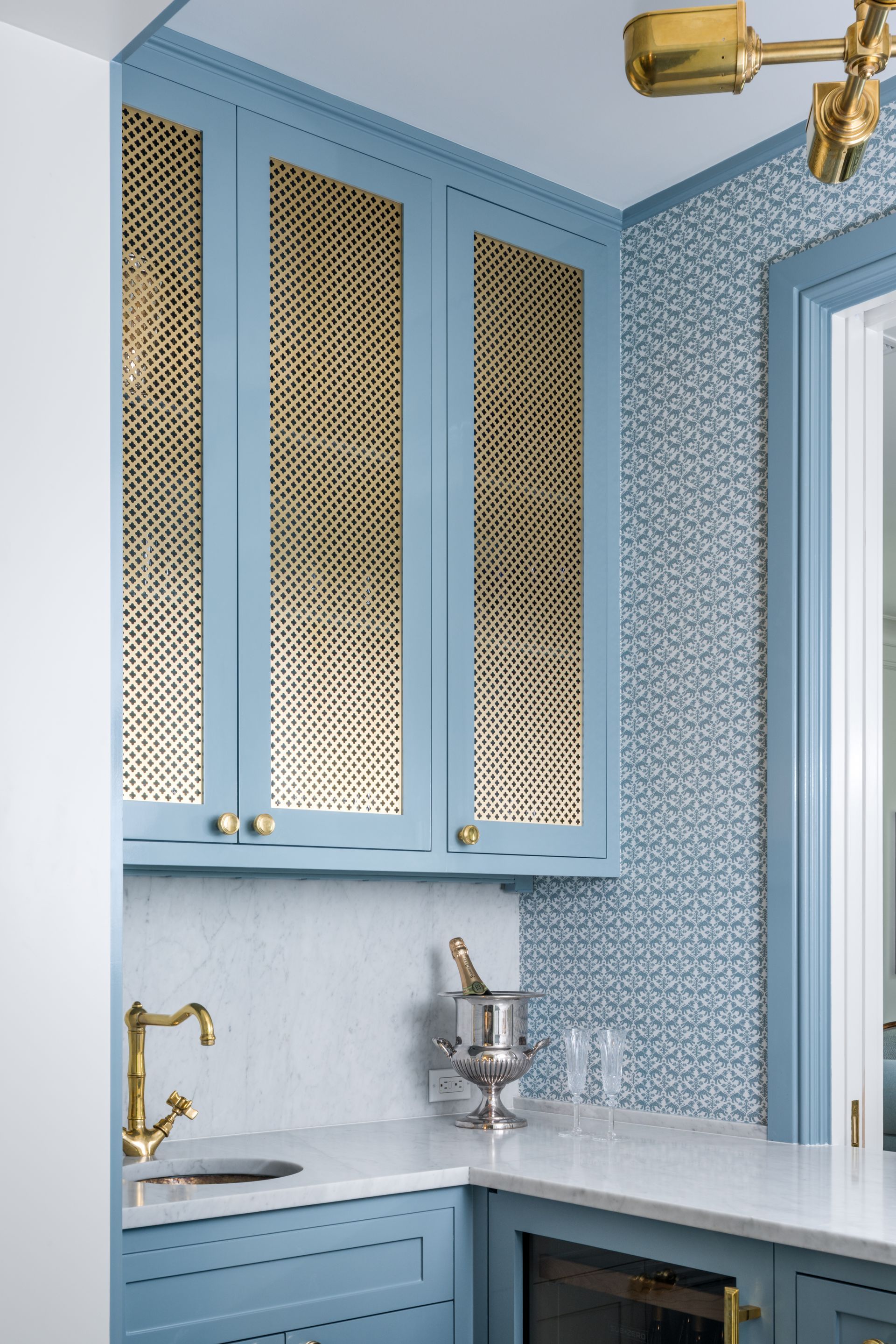 a kitchen with blue cabinets and gold trim and a sink .