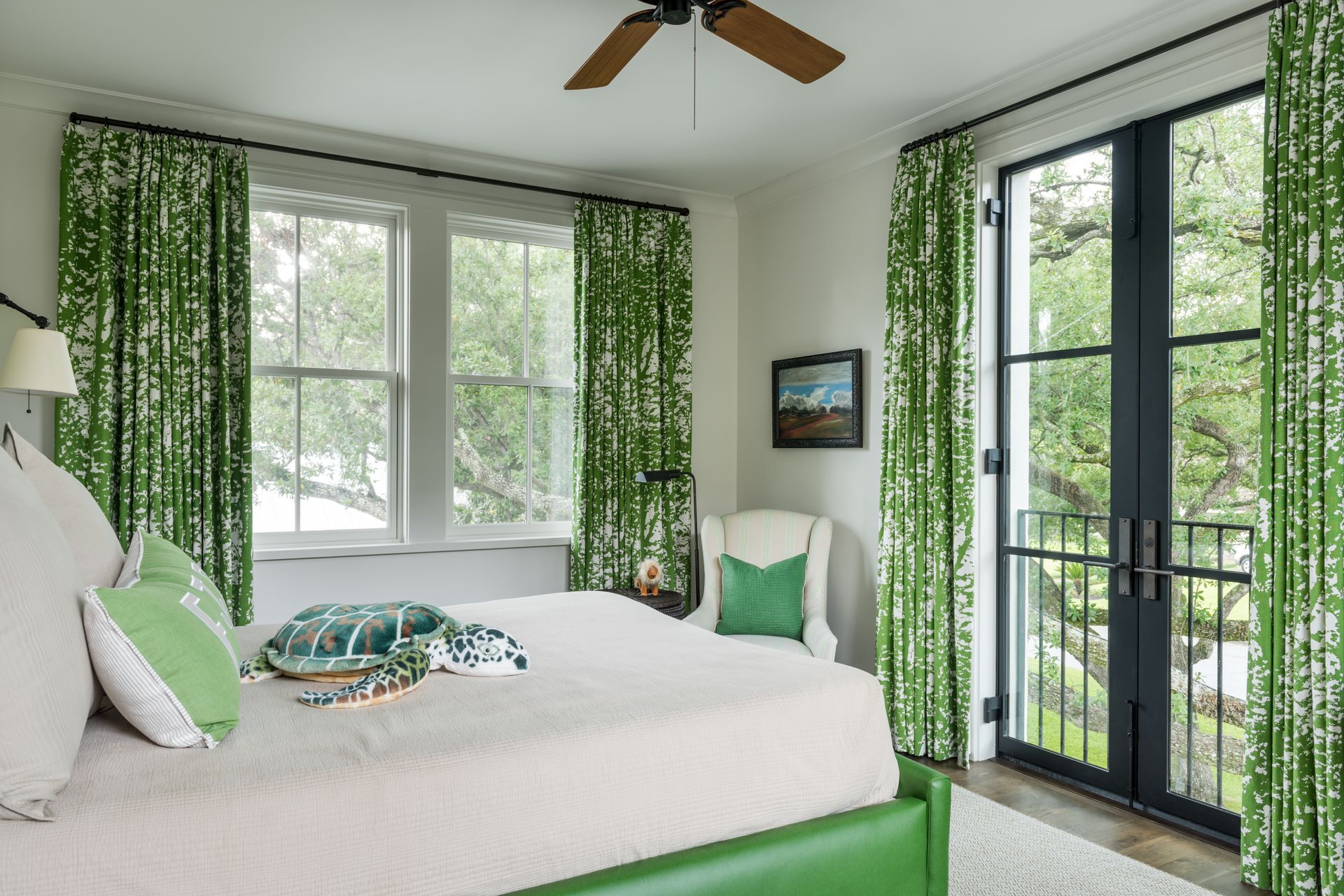 a bedroom with green curtains and a ceiling fan