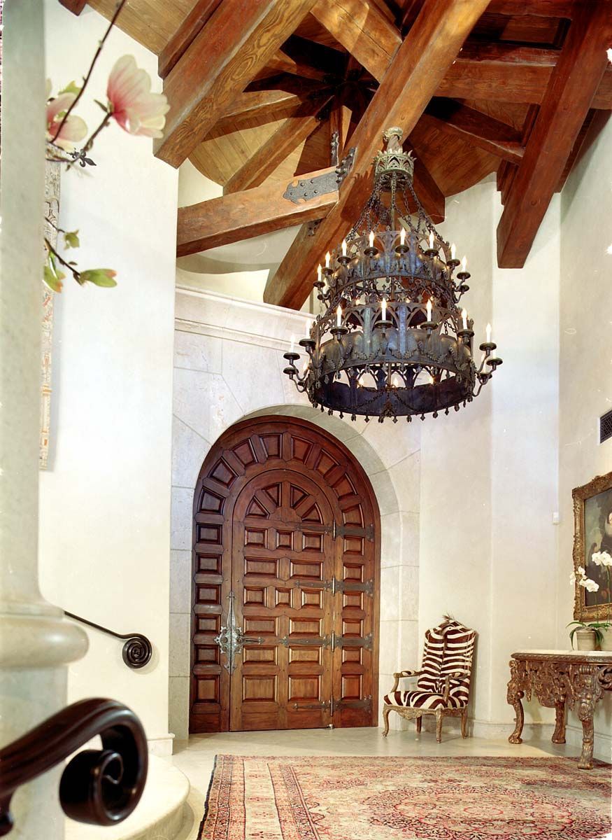 a hallway with a wooden door and a chandelier hanging from the ceiling
