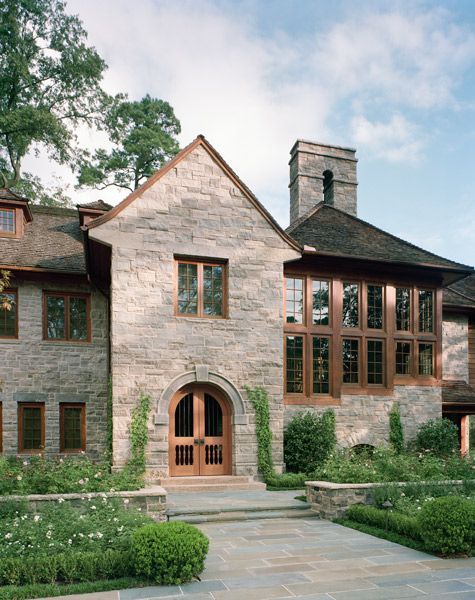a large stone house with lots of windows and a chimney