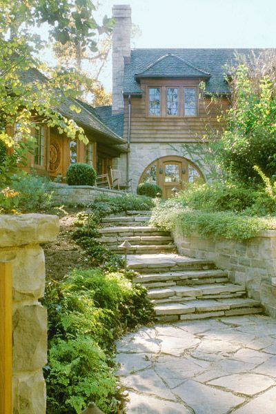 a stone walkway leading to a large house with stairs leading up to it .