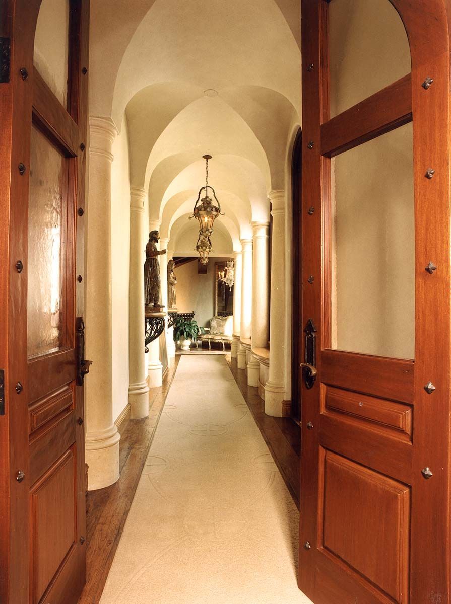 a long hallway with arched ceilings and wooden doors
