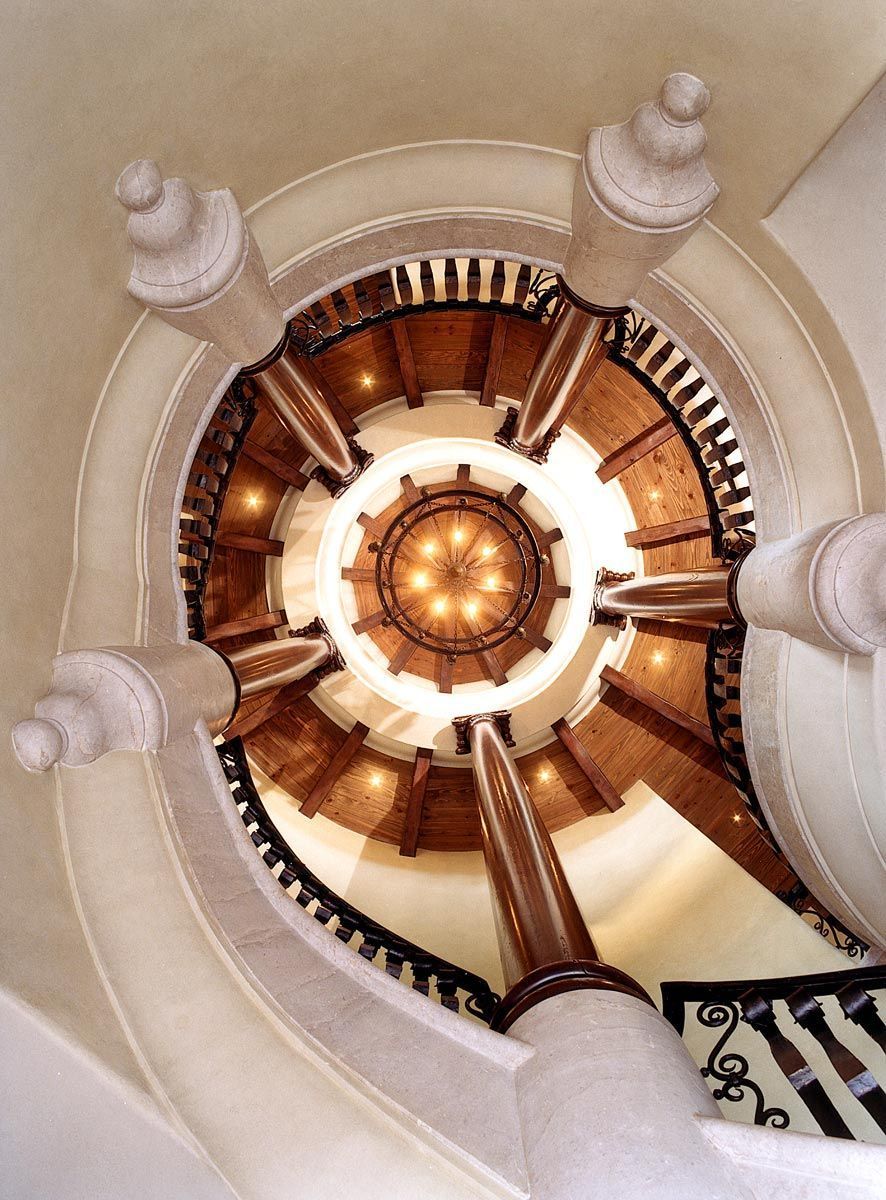 looking up at a spiral staircase with a chandelier