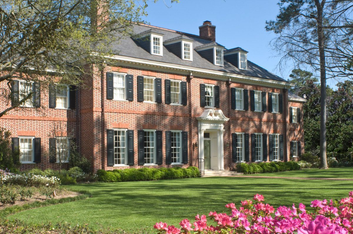 a large brick house with pink flowers in front of it