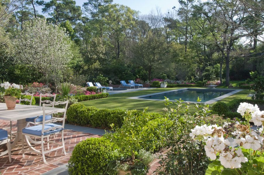 a patio with a table and chairs and a pool in the background