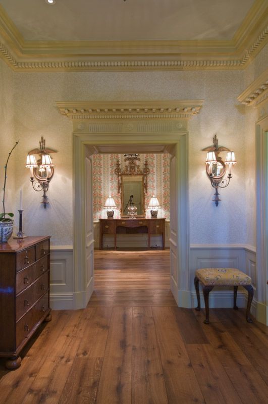 a hallway with hardwood floors , a dresser and a mirror .