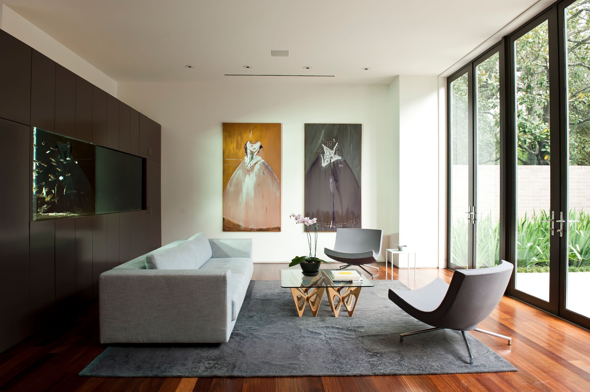 a living room with a couch , chairs , and paintings on the wall .