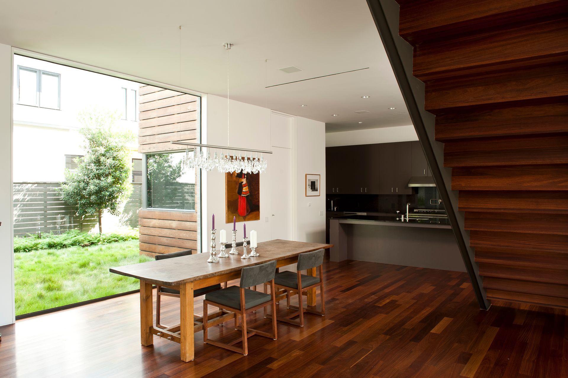 a dining room with a wooden table and chairs and a wooden staircase .