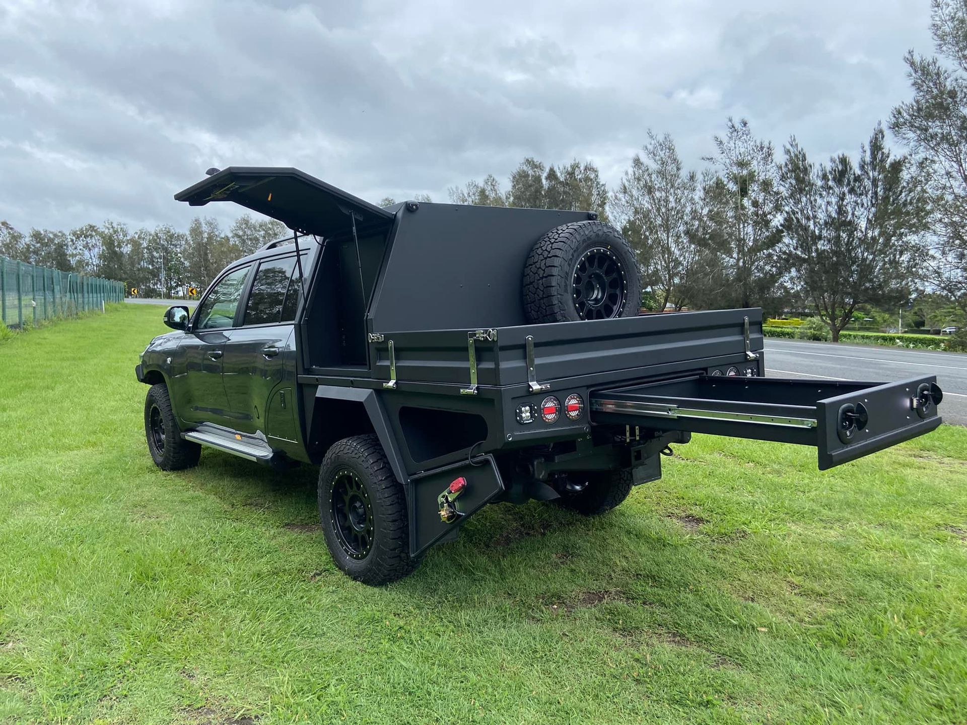 Black truck with a flatbed, canopy, and a pull-out drawer, parked on grass. — Custom RV Creations & Repairs in Sumner, QLD