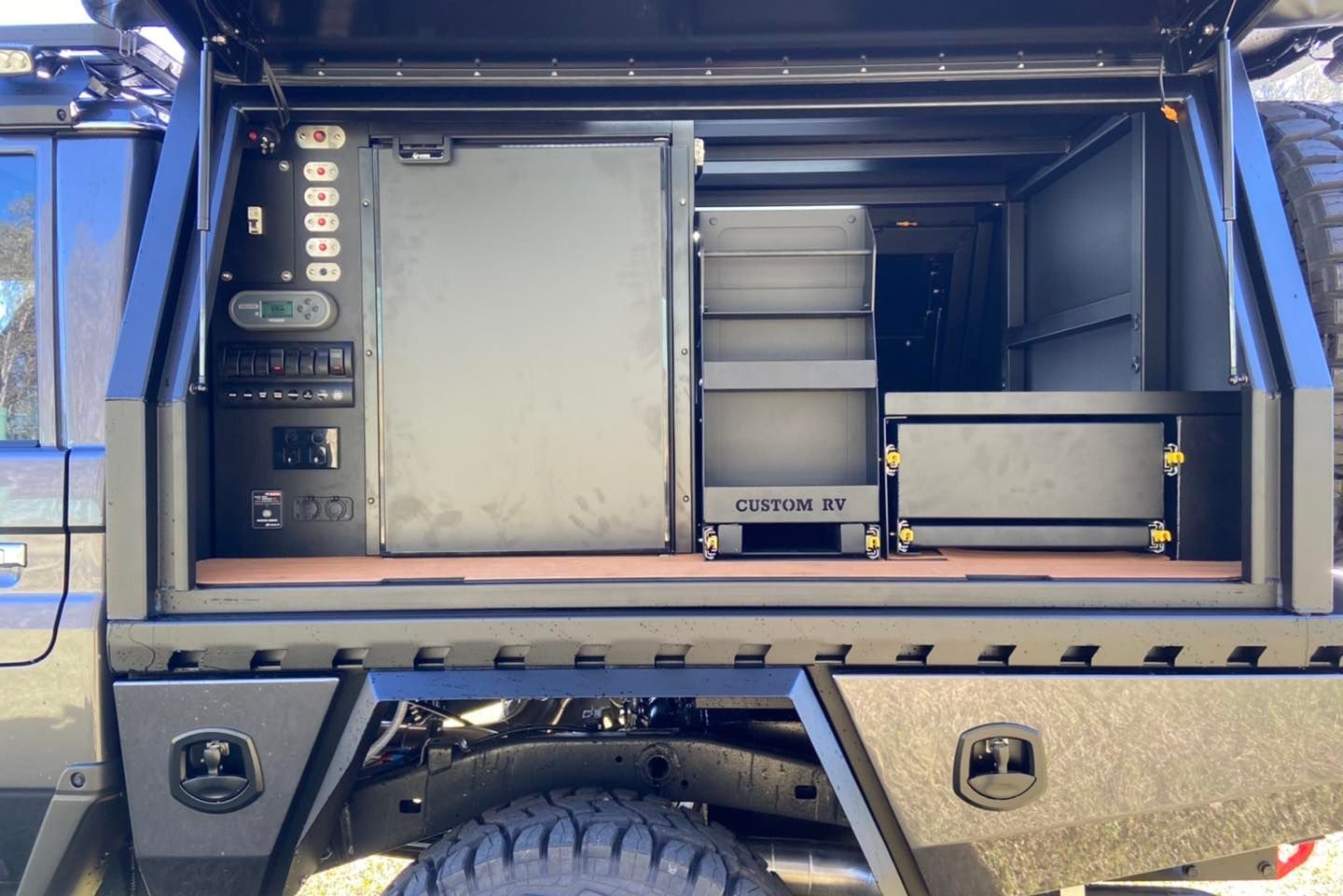 Dark truck bed with built-in storage, fridge, and shelving, all in shades of black. — Custom RV Creations & Repairs in Ipswich, QLD