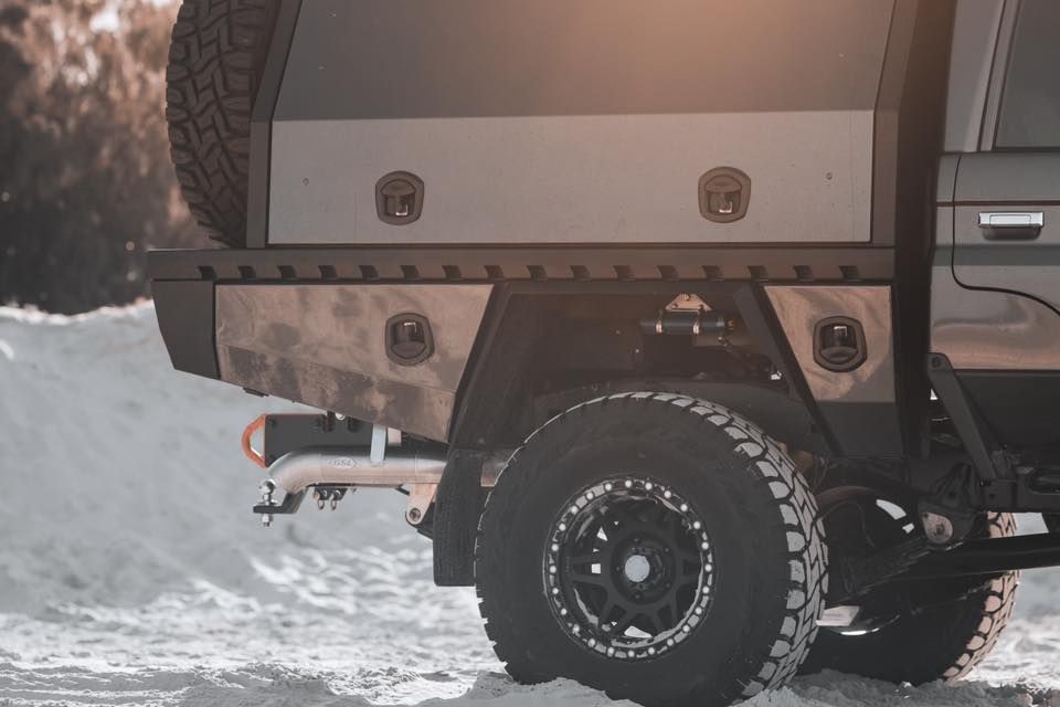 A customized pickup truck with a metal tray bed and off-road tires in a snowy setting. — Custom RV Creations & Repairs in Sumner, QLD