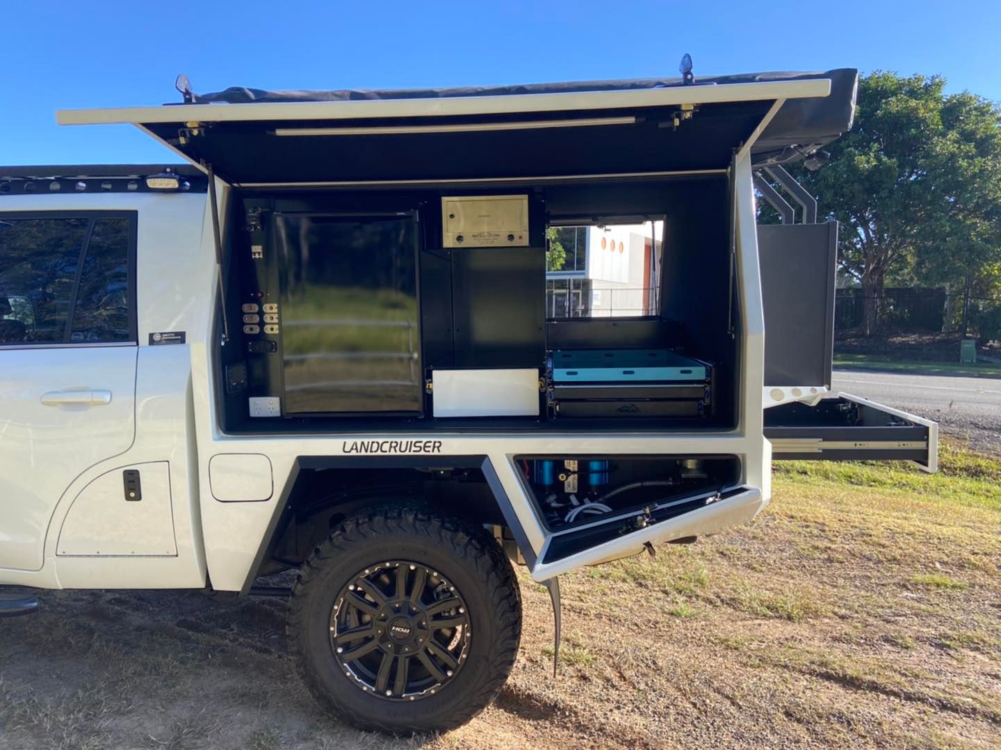 White truck bed with black camper shell; kitchen setup with fridge, cooktop, and storage. — Custom RV Creations & Repairs in Sumner, QLD