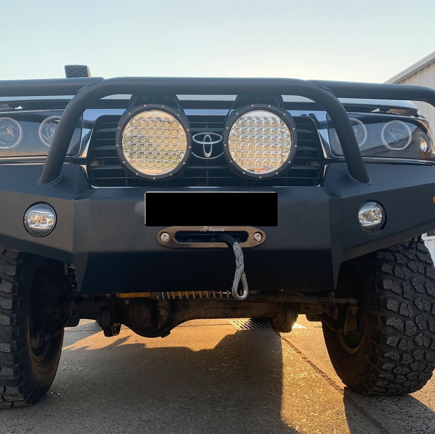 Black off-road truck with large round headlights and a winch; it is outdoors on a sunny day. — Custom RV Creations & Repairs in Sumner Park, QLD