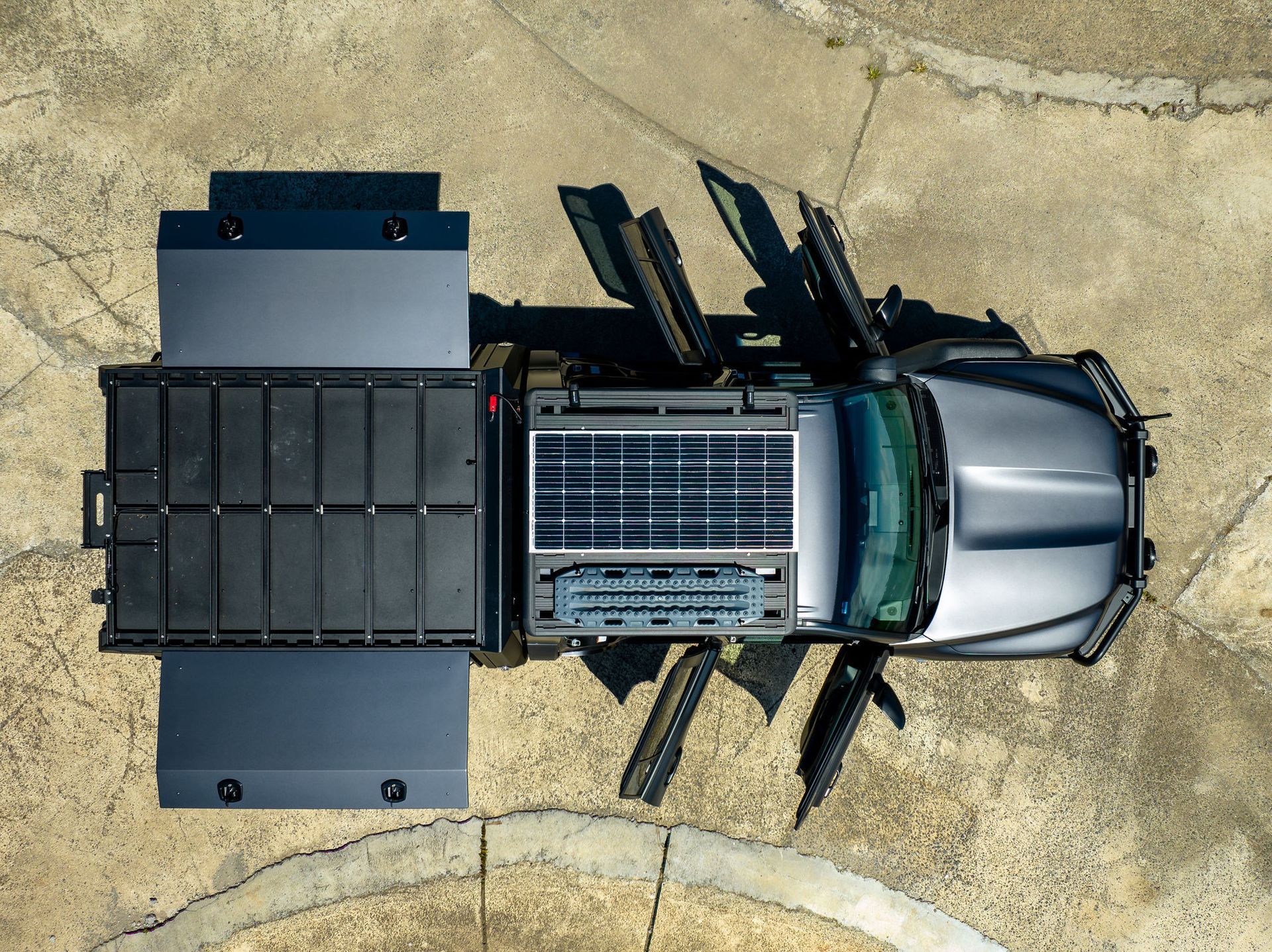 Overhead View of a Grey Off-road Vehicle With Open Doors and Solar Panels, on Concrete — Custom RV Creations in Sumner, QLD
