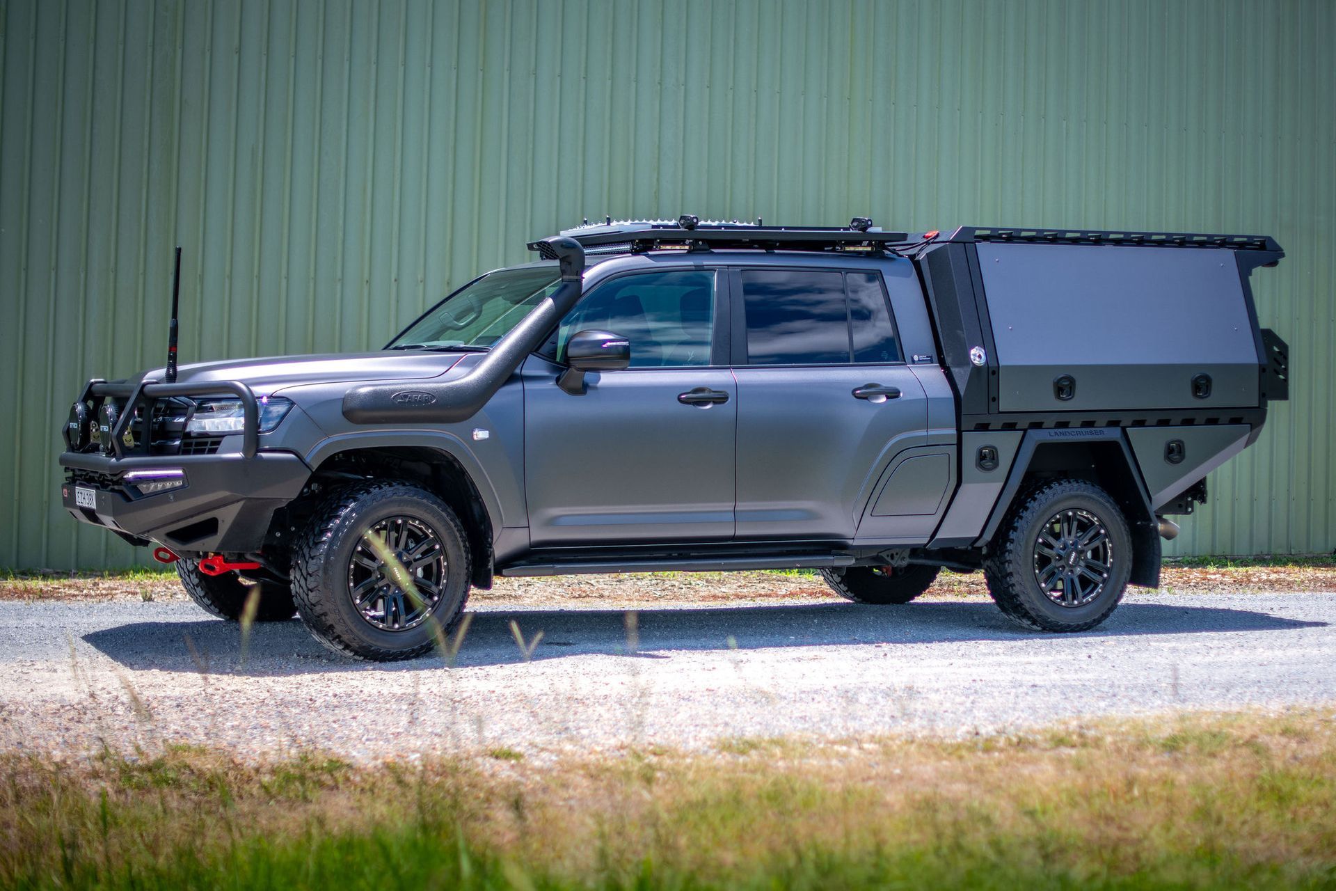 Grey Off-road Truck With Custom Tray, Roof Rack, and Snorkel Parked on a Gravel Road — Custom RV Creations in Sumner, QLD