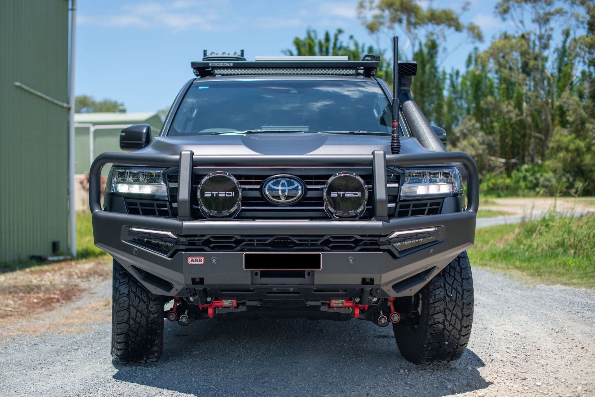 Black off-road truck with bull bar, spotlights, and roof rack parked outdoors on a sunny day. — Custom RV Creations & Repairs in Sumner, QLD