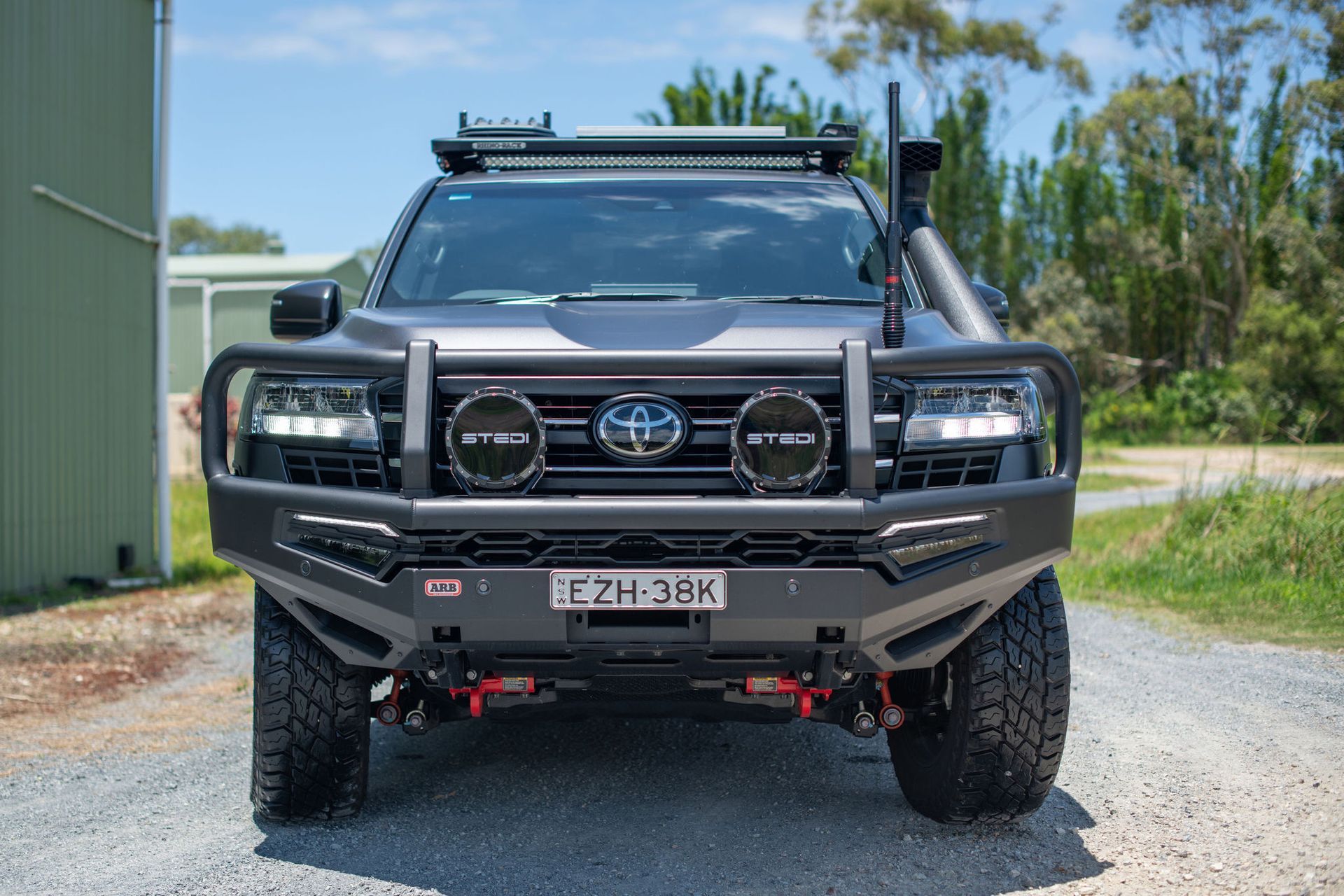 Grey Off-road Toyota Truck With Front Bull Bar, Spotlight, and Roof Rack on a Gravel Driveway — Custom RV Creations in Sumner, QLD