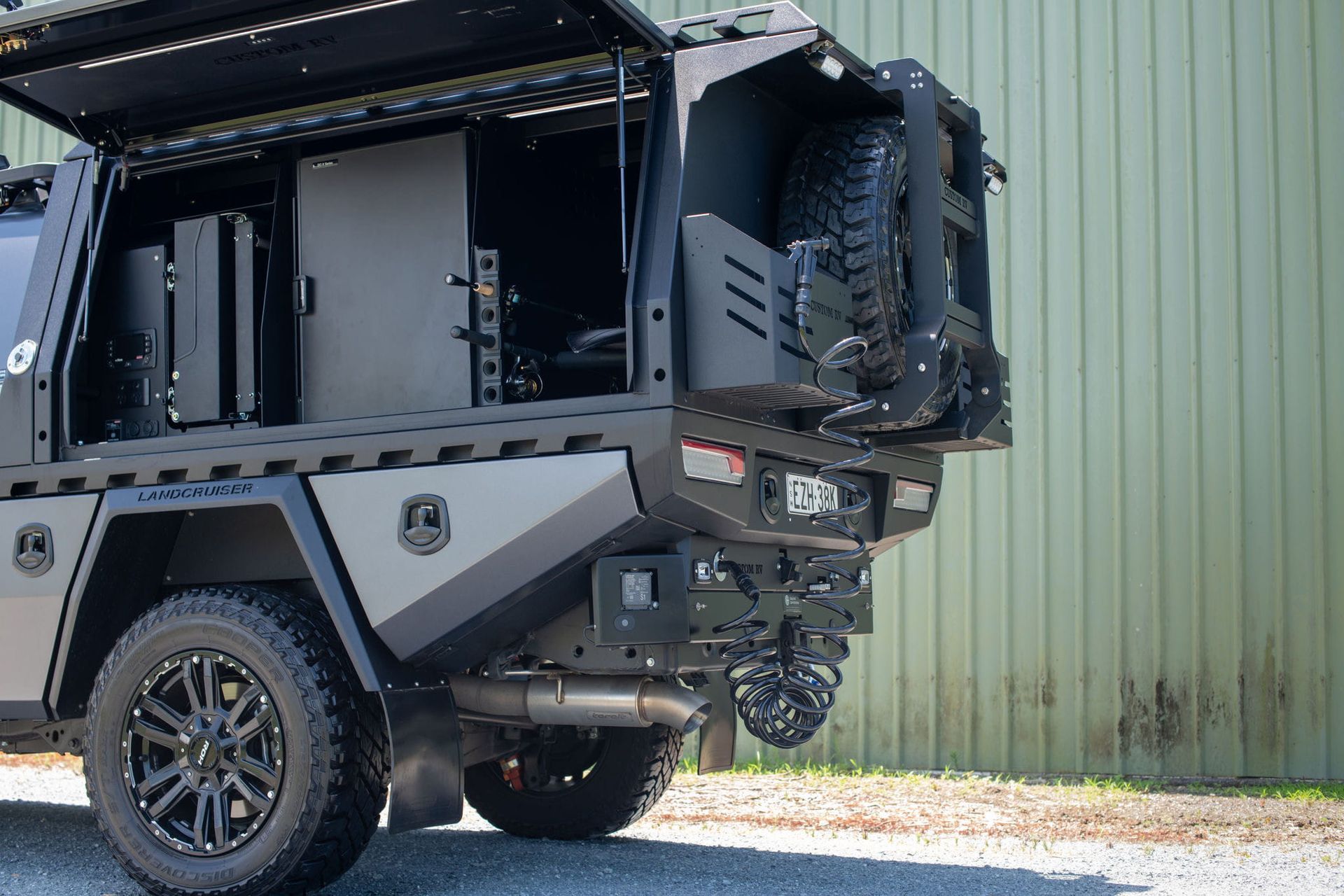 Dark grey customized utility truck with spare tire and equipment, parked next to a green wall. — Custom RV Creations & Repairs in Sumner, QLD