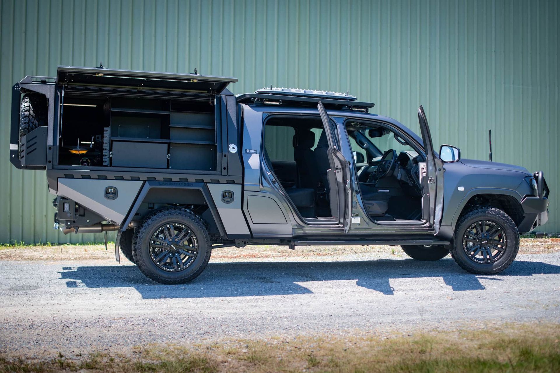 Gray custom off-road truck with opened doors and storage compartments, parked against a green wall. — Custom RV Creations & Repairs in Gold Coast, QLD