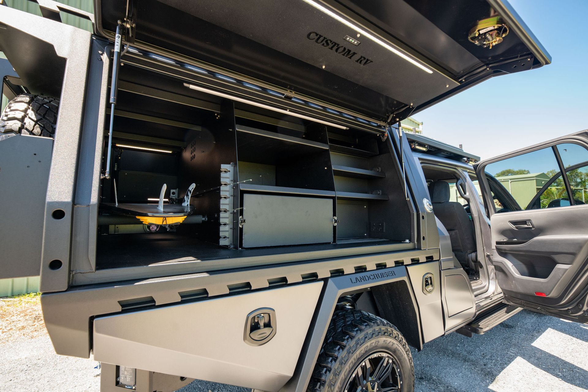 Dark Grey Truck Bed With Open Storage Compartments and Side Door — Custom RV Creations in Sumner, QLD