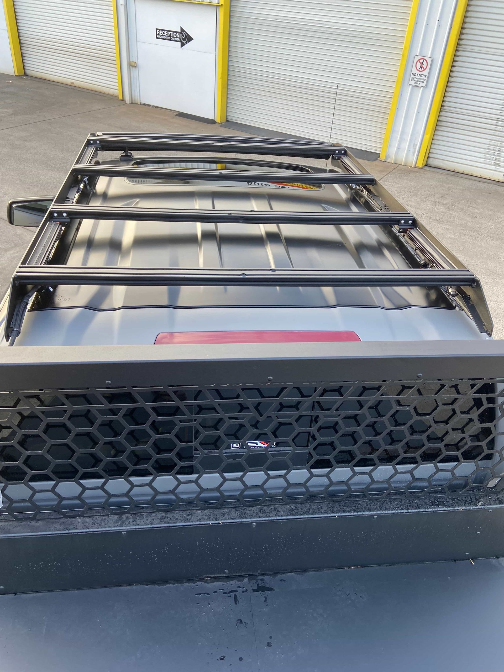 Black roof rack and grill on a vehicle. Black cargo rack mounted on a vehicle roof, with a protective grill at the rear. — Custom RV Creations & Repairs in Sumner, QLD