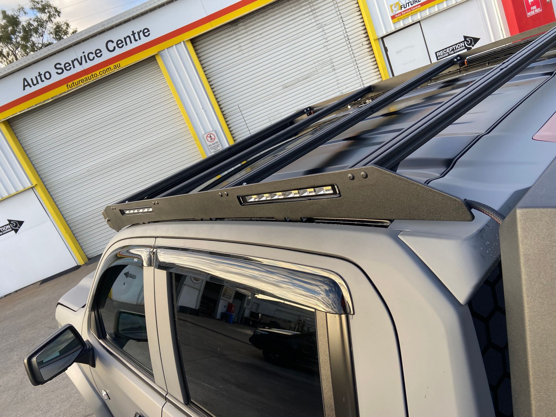 A Silver Pickup Truck With a Black Roof Rack in Front of an Auto Service Center — Custom RV Creations in Sumner, QLD