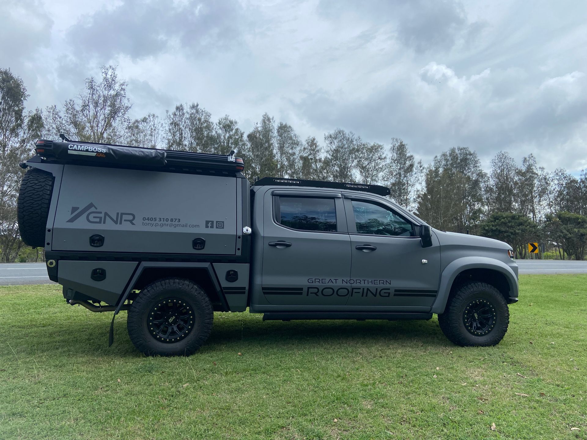 Grey Pickup Truck With a Custom Camper on Grass Beside a Road — Custom RV Creations in Sumner, QLD