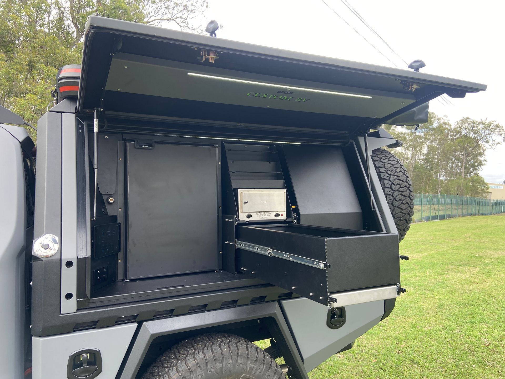 Truck Bed With a Black Camper Shell Open to Reveal Built-in Storage and Drawer — Custom RV Creations in Sumner, QLD