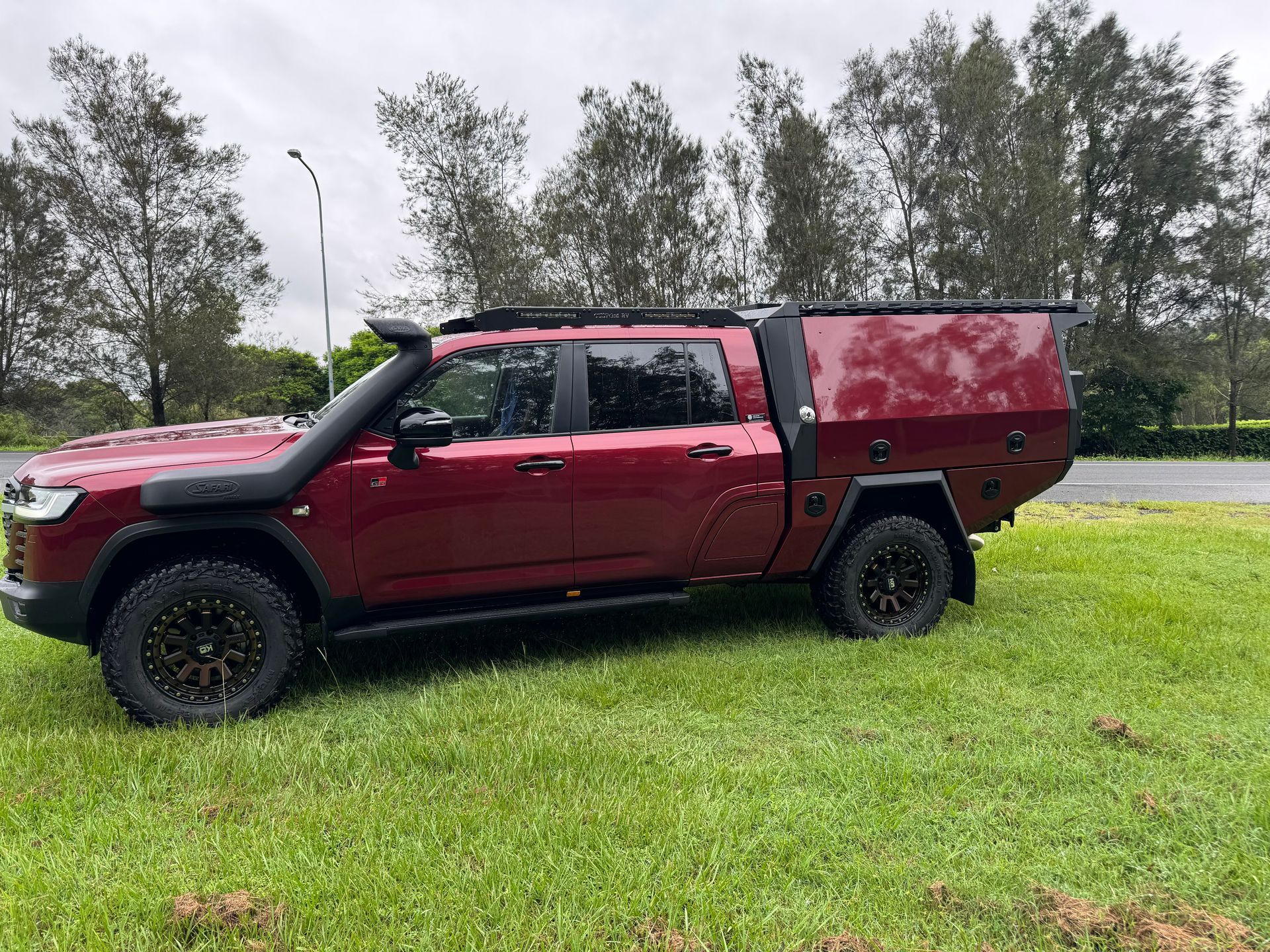 Dark Red Truck With Black Wheels and a Canopy Parked on Grass — Custom RV Creations in Sumner, QLD