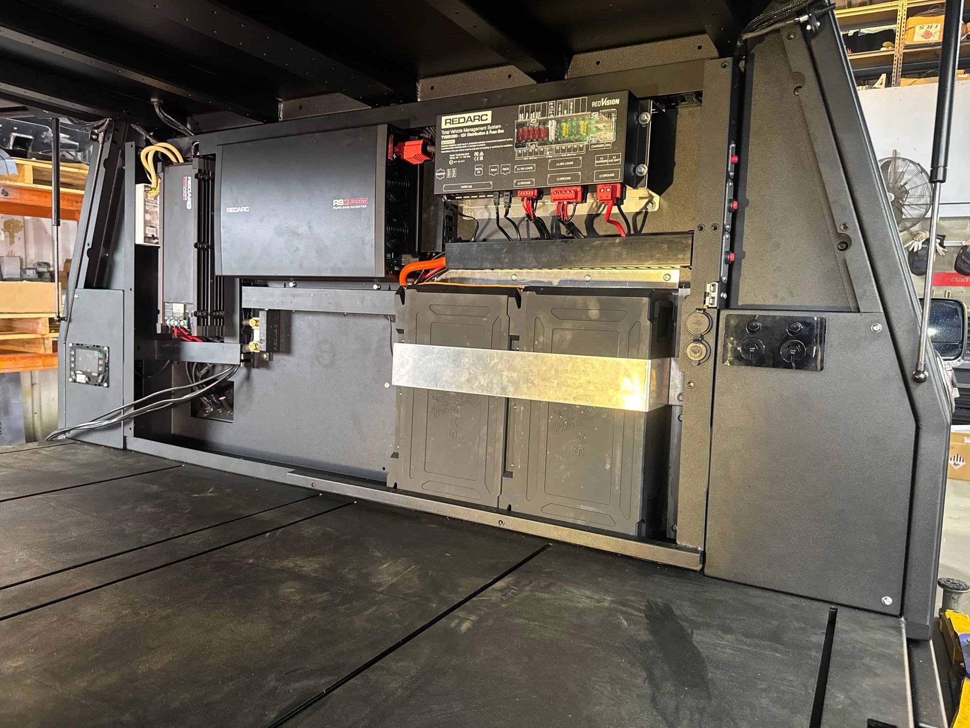 Black camper interior with electrical components and storage compartments. — Custom RV Creations & Repairs in Sumner Park, QLD