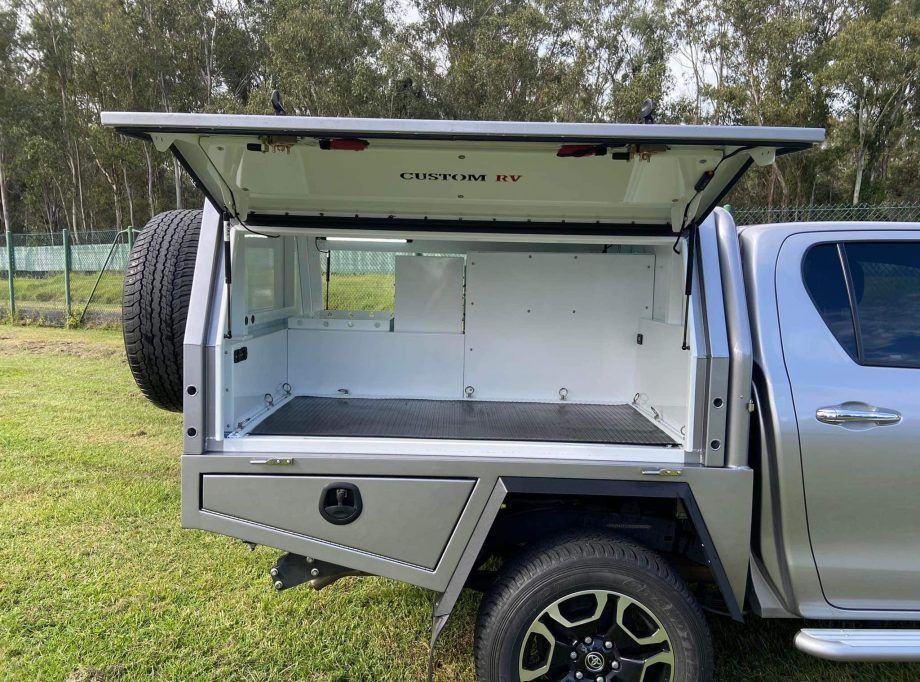 A Silver Vehicle With the Canopy Open is Parked in a Grassy Field — Custom RV Creations & Repairs in Sumner Park, QLD