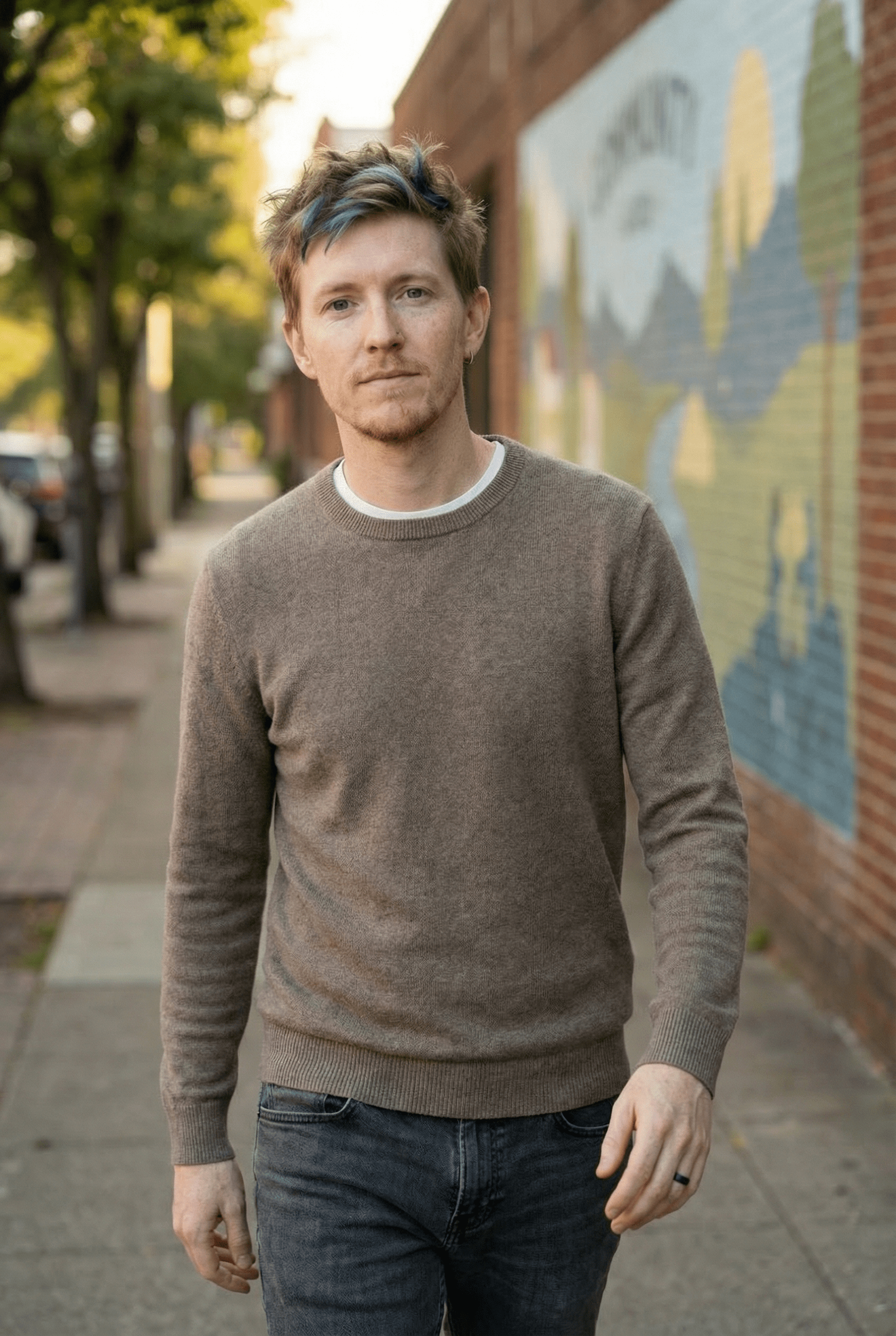 Person with dreadlocks seated on a couch, talking to another person out of frame.