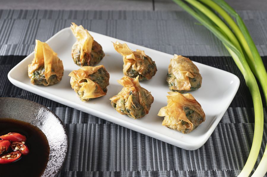 Plate of eight golden fried dumplings, with dipping sauce and green onions.