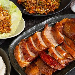 A black plate topped with sliced meat next to plates of food.