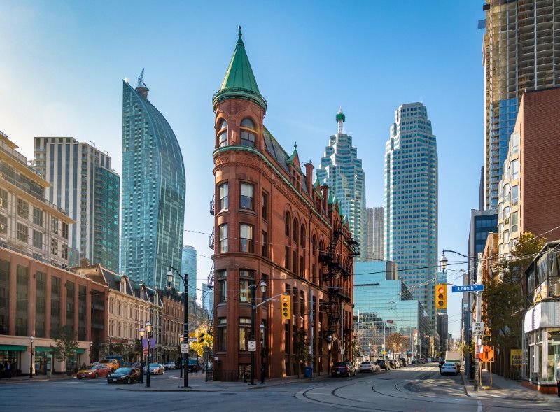A tall building with a green roof is in the middle of a city.