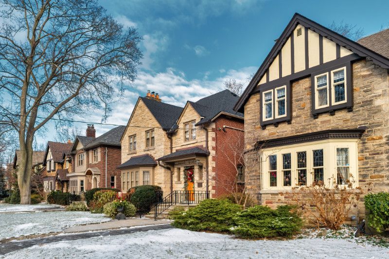 A row of houses on a snowy street with snow on the ground.