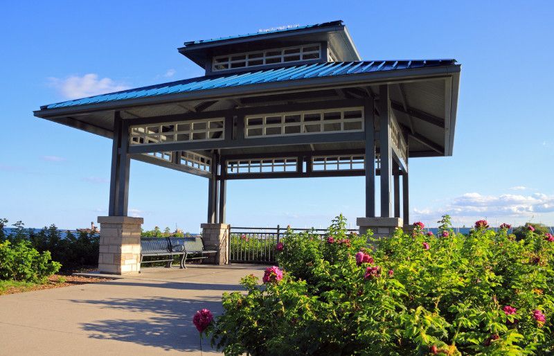 A gazebo with a blue roof is surrounded by flowers