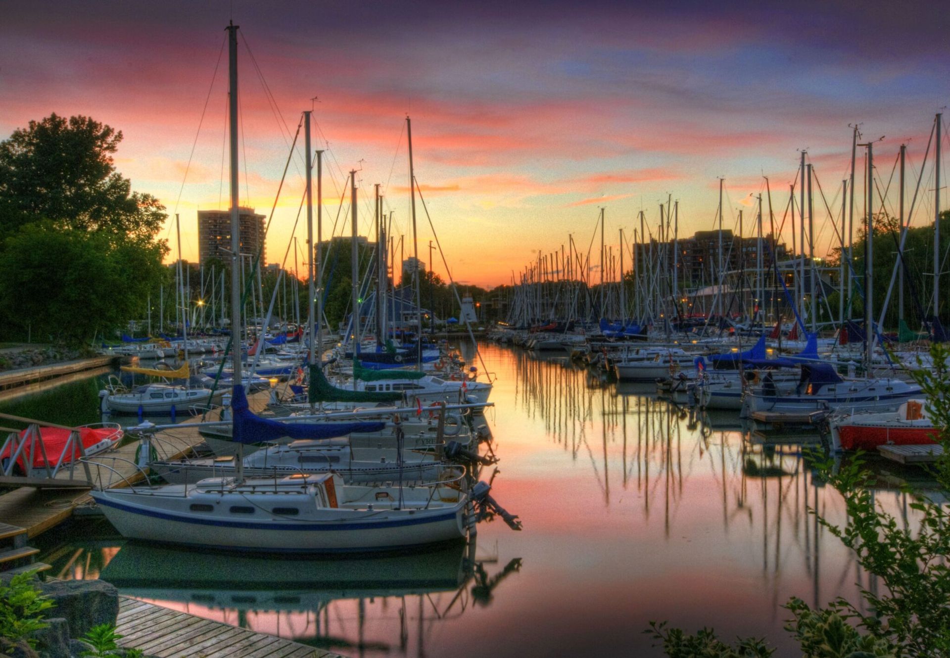 A bunch of boats are docked in a harbor at sunset in Oakville, Ontario
