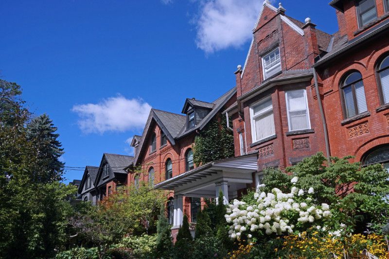 A row of brick houses with flowers in front of them on a sunny day.