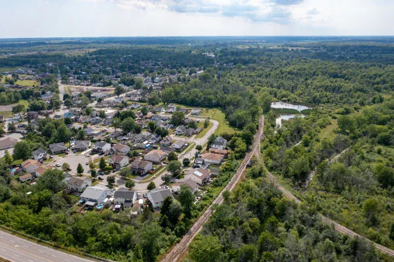An aerial view of a residential area surrounded by trees and a train track.