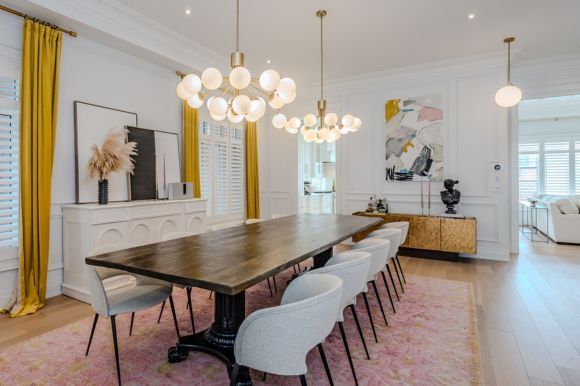 A dining room with a long table and chairs and a chandelier.