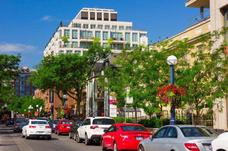A row of cars are parked on the side of a city street.