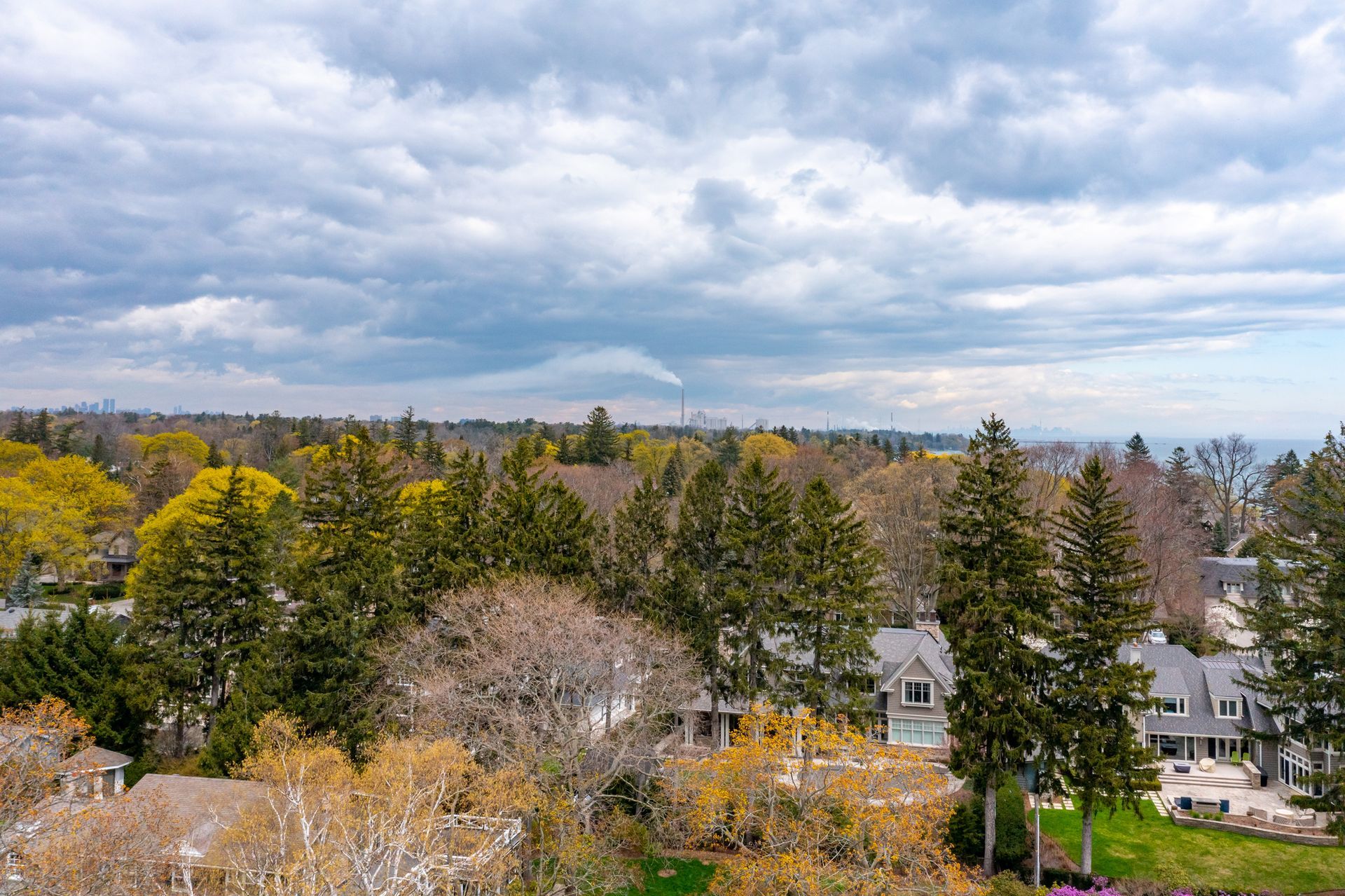 An aerial view of a residential area surrounded by trees and houses on a cloudy day.