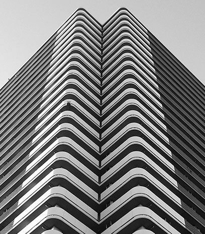 A black and white photo of a tall building with a chevron pattern on the balconies.