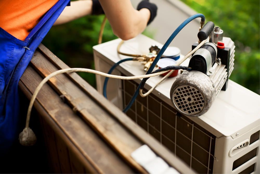 A Man Is Working on An Air Conditioner on A Balcony — Gordon's Air Conditioning & Refrigeration Services in Caloundra, QLD