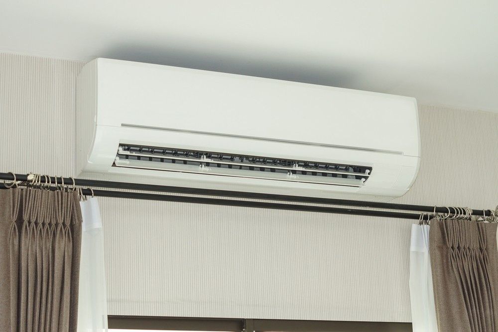 White Air Conditioner Mounted on Wall Above Window — Gordon's Air Conditioning & Refrigeration Services in Maleny, QLD